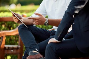 Two men in suits look at an ipad.
